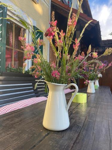 a white vase filled with pink flowers on a wooden table at Runas Air Muc Park Sleep & Fly in Hallbergmoos