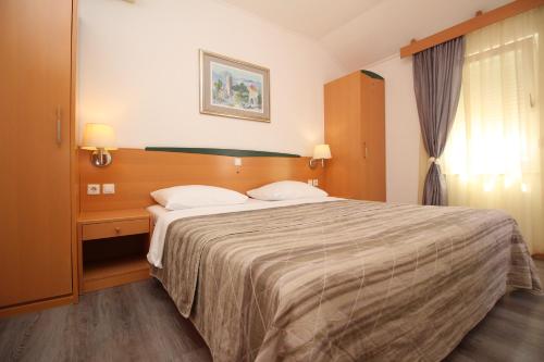 een slaapkamer met een groot bed met 2 kussens bij Villas Corinthia in Baška