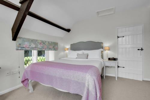 a white bedroom with a large bed and a window at Cascade Cottage in Exford