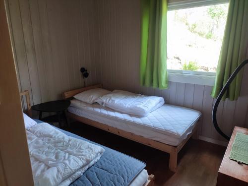 Zimmer mit 2 Betten und einem Fenster mit grünen Vorhängen in der Unterkunft Strandheim Two-Bedroom Cottage in Birkeland