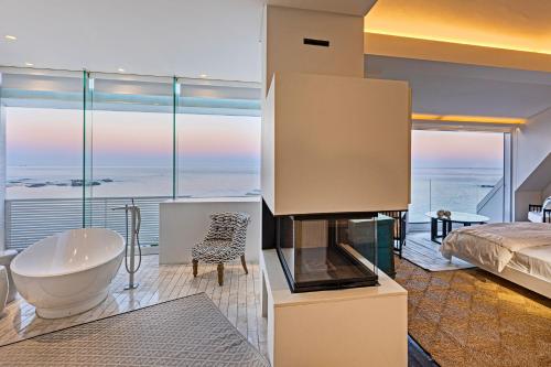 a bedroom with a tub and a bed and a view of the ocean at Clifton Ezulwini in Cape Town