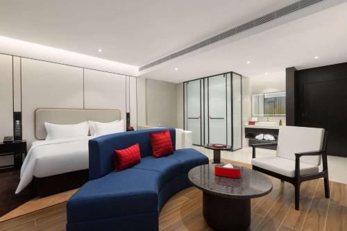 a hotel room with a bed and a blue couch at Ramada by Wyndham Xishuangbanna Jinghong in Jinghong