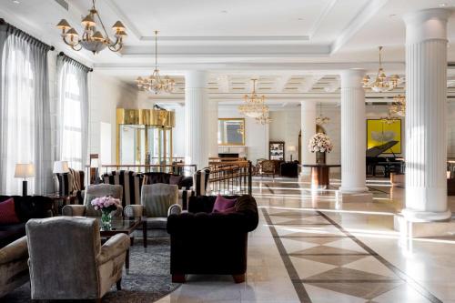 a lobby with couches and chairs and a piano at Grand Hotel Vilnius, Curio Collection by Hilton in Vilnius