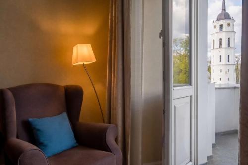 a chair with a blue pillow sitting next to a window at Grand Hotel Vilnius, Curio Collection by Hilton in Vilnius