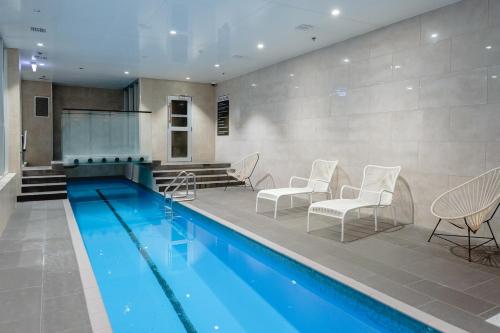 a swimming pool with chairs and a table at Apartment with Brilliant views in Auckland CBD in Auckland