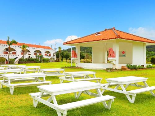 una fila de mesas de picnic frente a un edificio en Resort Hotel Kume Island, en Kumejima