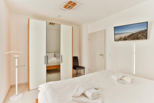 a white bedroom with a bed and a mirror at Landhaus Wreechen mit Dachterrasse in Putbus