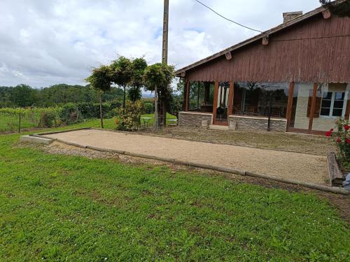 a building with a walkway next to a grass field at Gîte de Pagalot au cœur du vignoble in Virazeil