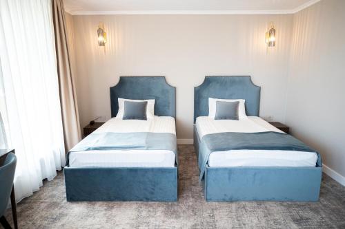 two beds in a room with blue furniture at Hotel Meridian in Cluj-Napoca