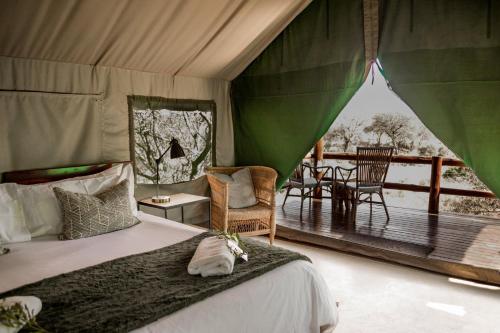 a bedroom with a bed and a deck with a table at Sausage Tree Safari Camp in Balule Game Reserve