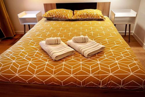 un grand lit avec deux serviettes dessus dans l'établissement Savane - Appart. tout équipé rénové, avec terrasse, à Vichy
