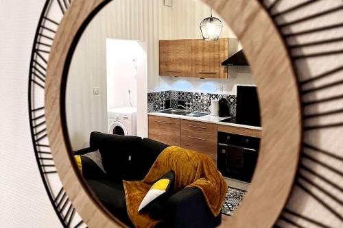un miroir reflétant le salon avec un canapé dans l'établissement Savane - Appart. tout équipé rénové, avec terrasse, à Vichy
