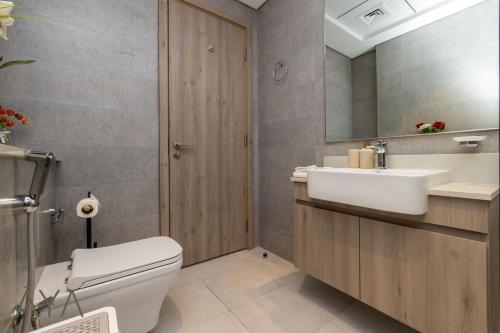 a bathroom with a toilet and a sink and a mirror at Stylish 2BR Apartment at Dubai Hills with Pool Access By ĀYA Boutique in Dubai