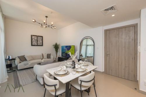 a dining room and living room with a table and chairs at Stylish 2BR Apartment at Dubai Hills with Pool Access By ĀYA Boutique in Dubai