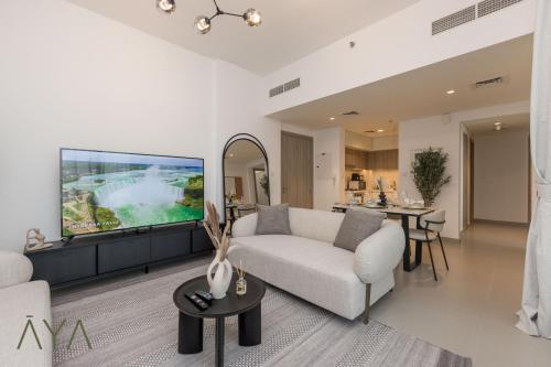 a living room with a white couch and a tv at Stylish 2BR Apartment at Dubai Hills with Pool Access By ĀYA Boutique in Dubai