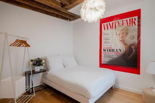 une chambre avec un lit blanc et une affiche de film dans l'établissement Paris Center Greneta residence, à Paris