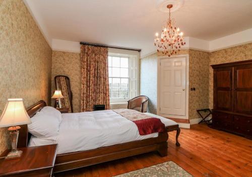 een slaapkamer met een bed, een tafel en een kroonluchter bij Preston House in Abbeyleix