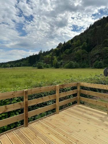 a wooden deck with a fence and a field at The Roecliffe Sea View 9 in Dunoon