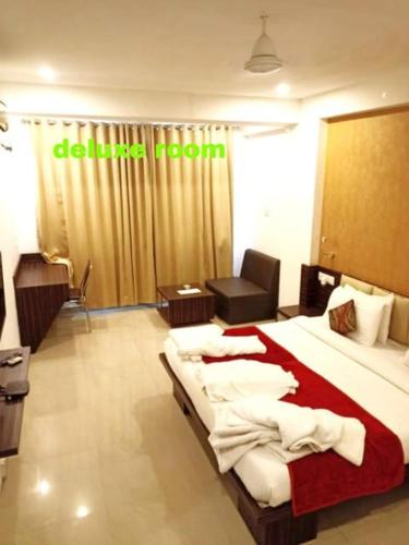 a hotel room with a bed and a chair at Hotel Balaji Central in Ratlām
