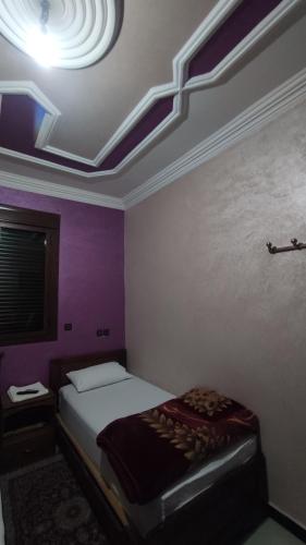 a bedroom with a bed with purple walls and a ceiling at IAZAL Hotel Ouarzazate in Ouarzazate