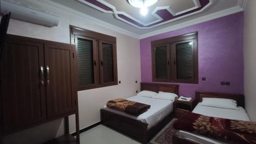 a bedroom with two beds and purple walls at IAZAL Hotel Ouarzazate in Ouarzazate