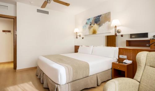 ein Hotelzimmer mit einem Bett und zwei Stühlen in der Unterkunft Ilunion Les Corts Spa in Barcelona