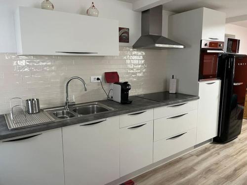 a kitchen with white cabinets and a sink and a refrigerator at Chez Mat - 4 pers - Proche Obernai in Bernardswiller