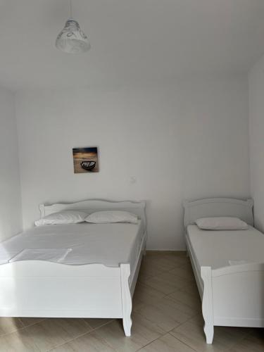 two beds in a room with white walls at Guesthouse Butrinti in Ksamil