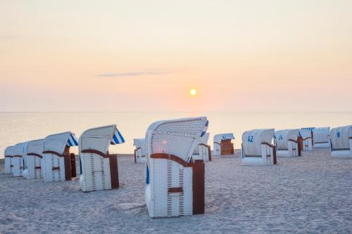 a row of chairs on the beach at sunset at Studio-Apartment Piccolino 26 in Timmendorfer Strand