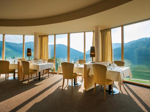 a restaurant with tables and chairs and large windows at Almwellness Hotel Pierer in Fladnitz an der Teichalm