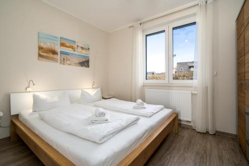 a white bedroom with a bed with two towels on it at Strandhaus 3 EG in Röbel