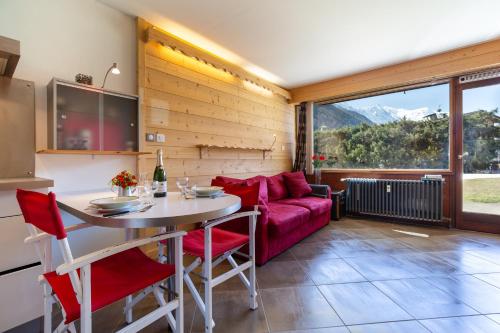 een woonkamer met een tafel en een rode bank bij Résidence Grands Montets 133 ski in-ski out - Happy Rentals in Chamonix-Mont-Blanc