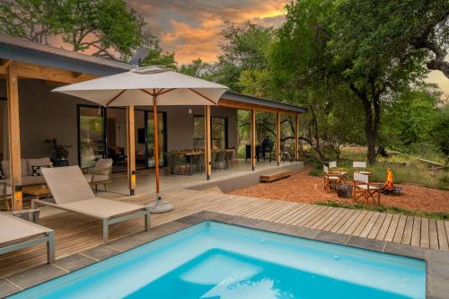 una casa con piscina e ombrellone di Nomads Den Luxury Villa with Riverbed View a Hoedspruit