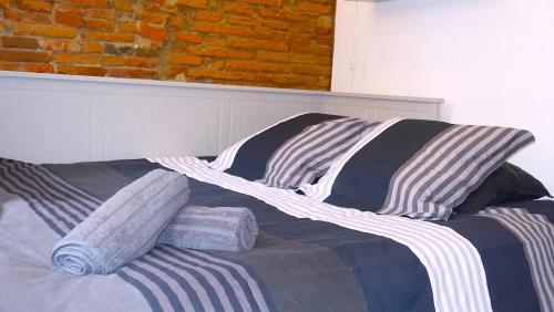 un lit avec des oreillers rayés et un mur de briques dans l'établissement Toulouse-Cyprien, typique à 10' Capitole & Carmes, à Toulouse