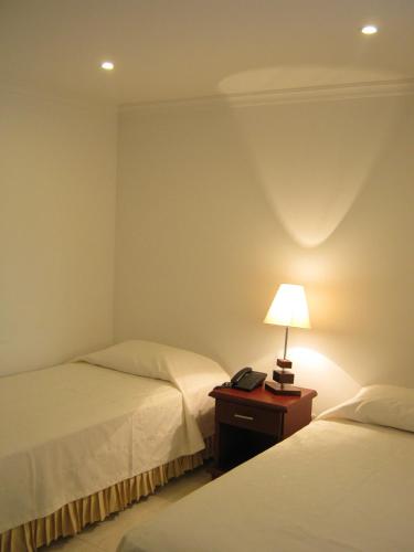 a bedroom with two beds and a lamp on a table at Hotel Sol Dorado in Villavicencio