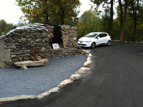 a white car parked next to a stone wall at Aux Pays Des Sucs in Saint-Hostien