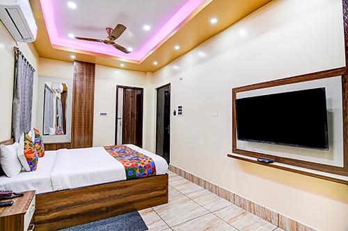una camera da letto con una grande TV a schermo piatto a parete di FabHotel Kanan Inn a kolkata