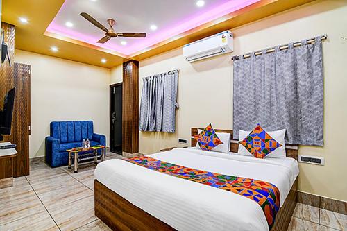 una camera con letto e sedia blu di FabHotel Kanan Inn a kolkata