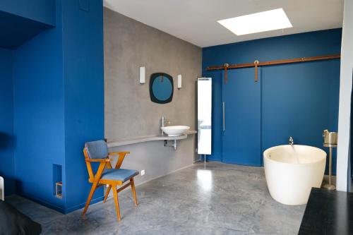 La salle de bains est pourvue de murs bleus, d'une baignoire et d'un lavabo. dans l'établissement Maison exceptionnelle esprit loft avec piscine, à Pézenas