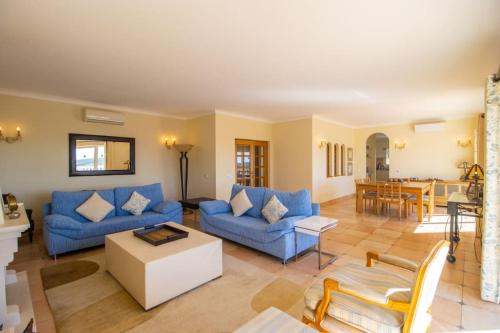 a living room with blue couches and a table at Parque da Floresta villa 209 with pool on golf resort in Budens