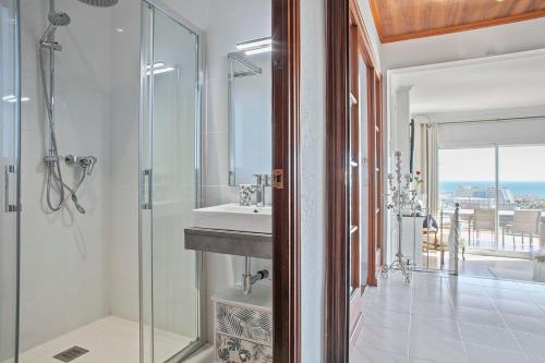 a bathroom with a sink and a glass shower at HOUSE WITH AMAZING VIEWS , OVERLOOKING THE FESTIVAL TOWN OF SITGES in Sitges