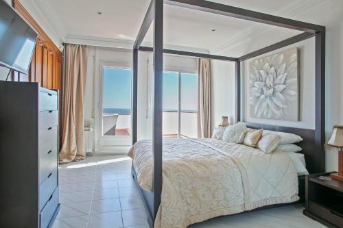a bedroom with a canopy bed with a view of the ocean at HOUSE WITH AMAZING VIEWS , OVERLOOKING THE FESTIVAL TOWN OF SITGES in Sitges