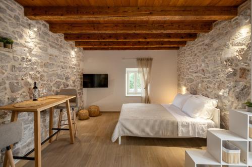 a stone walled bedroom with a bed and a desk at Villa Casa di Perla in Primošten