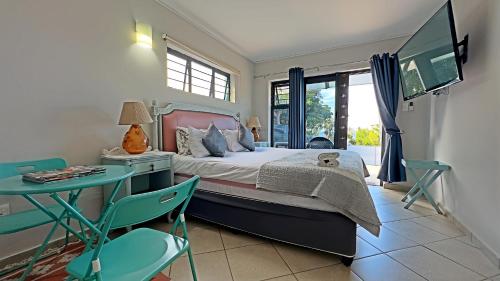 1 dormitorio con 1 cama, mesa y sillas en At The Sea Ballito, en Ballito