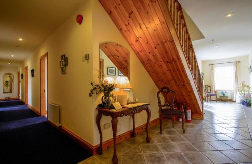 a hallway with a stairway with a table and a stairwayngth at Errisbeg Lodge Bed + Breakfast in Roundstone