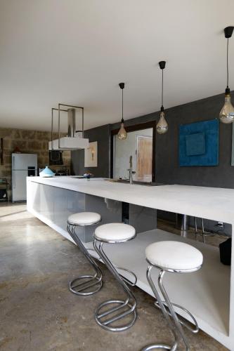 une cuisine avec un comptoir avec trois tabourets dans l'établissement Maison exceptionnelle esprit loft avec piscine, à Pézenas