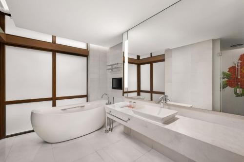 a bathroom with a tub and a sink and a mirror at Le Méridien Xiamen in Xiamen