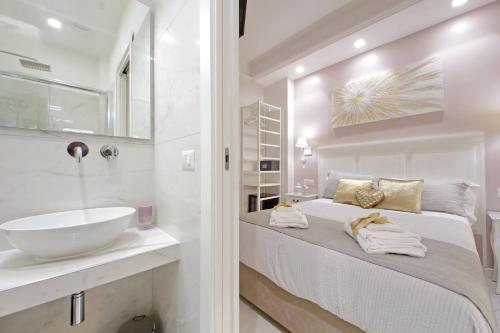 a white bathroom with a sink and a bed at Roman Holiday Charming in Rome