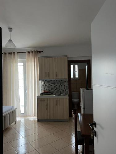 a kitchen with wooden cabinets and a table and a refrigerator at Guesthouse Butrinti in Ksamil