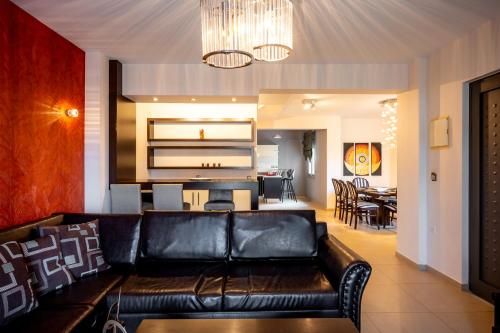 a living room with a leather couch and a dining room at Villa Miami in Agia Marina Nea Kydonias